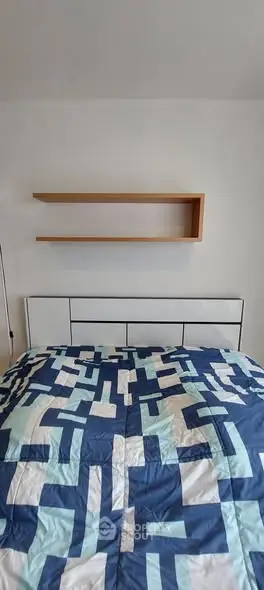 Modern bedroom with geometric patterned bedding and minimalist wall shelf design.