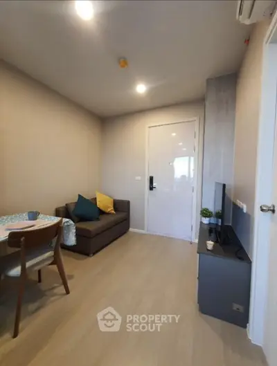 Modern cozy living room with sofa, TV, and dining area in a compact apartment.