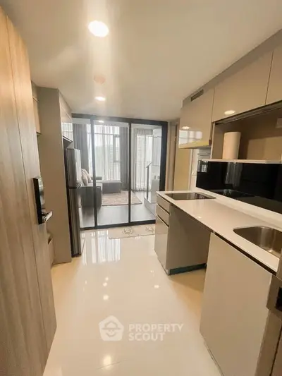Modern kitchen with sleek cabinetry and open layout leading to a stylish living room with large windows.