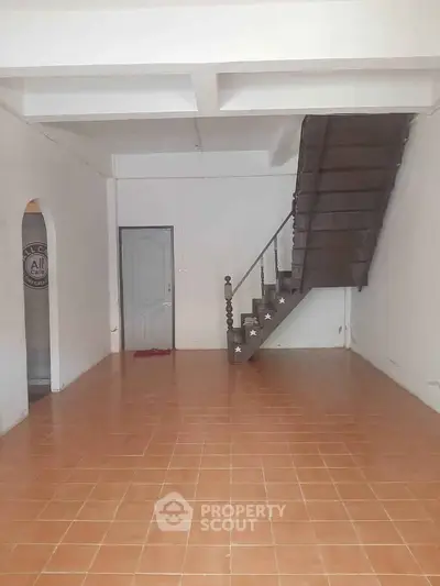 Spacious interior with tiled floor and wooden staircase, ideal for customization.