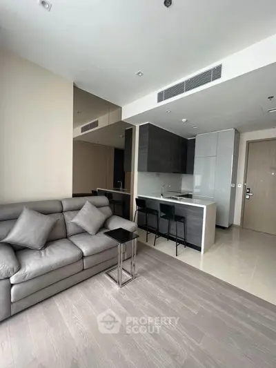 Modern living room with sleek kitchen and cozy seating area in open layout apartment.
