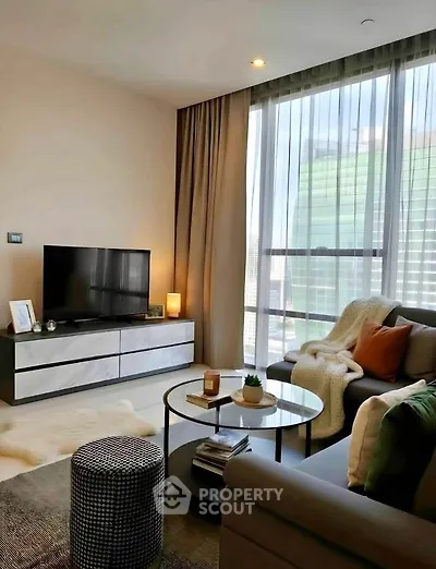Modern living room with large windows, stylish furniture, and cozy decor in a high-rise apartment.
