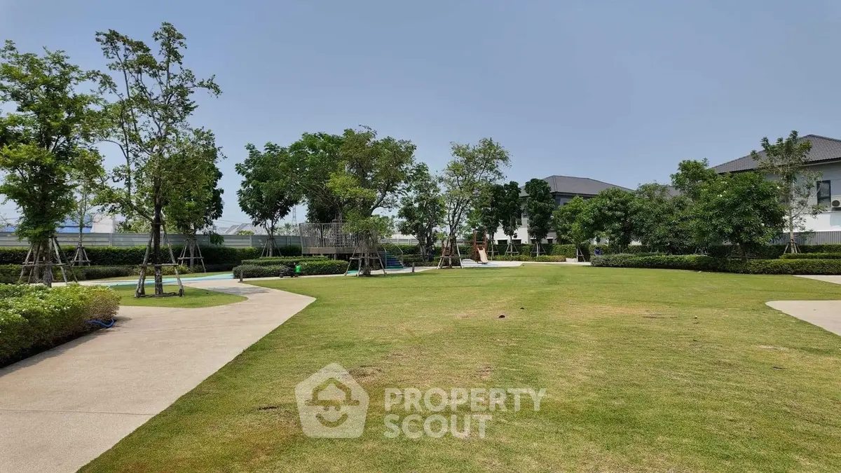 Spacious garden area in modern residential complex with lush greenery and pathways.
