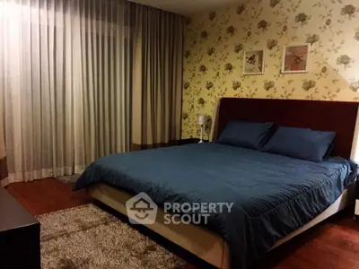 Cozy bedroom with floral wallpaper and elegant blue bedding, perfect for relaxation.