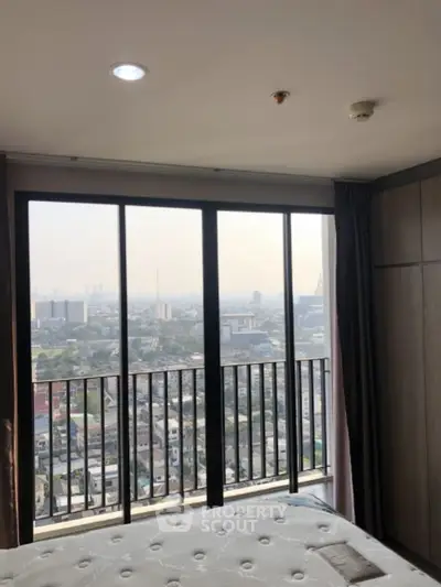 Stunning city view from a modern high-rise bedroom with floor-to-ceiling windows.