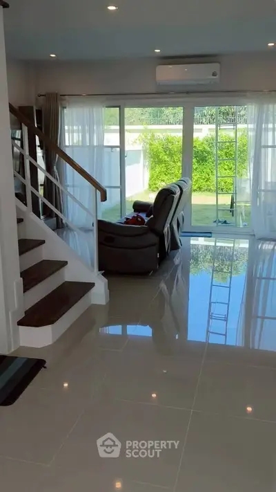 Spacious living room with modern staircase and garden view