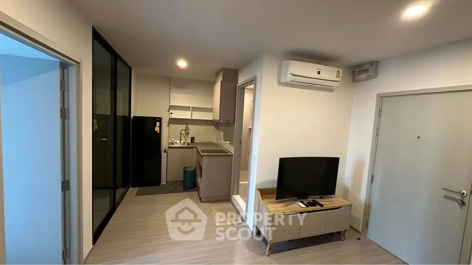 Modern apartment interior with compact kitchen and living area, featuring air conditioning and sleek design.