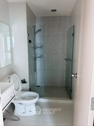 Modern bathroom with glass shower and sleek fixtures in contemporary apartment.