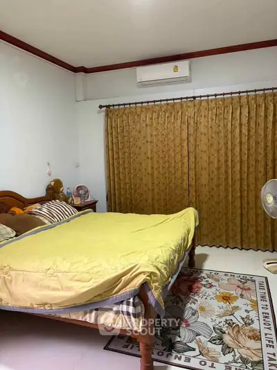 Cozy bedroom with wooden bed, floral rug, and air conditioning, perfect for relaxation.
