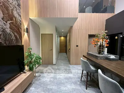 Modern living room with stylish decor and open layout, featuring a sleek TV unit and elegant bar seating.