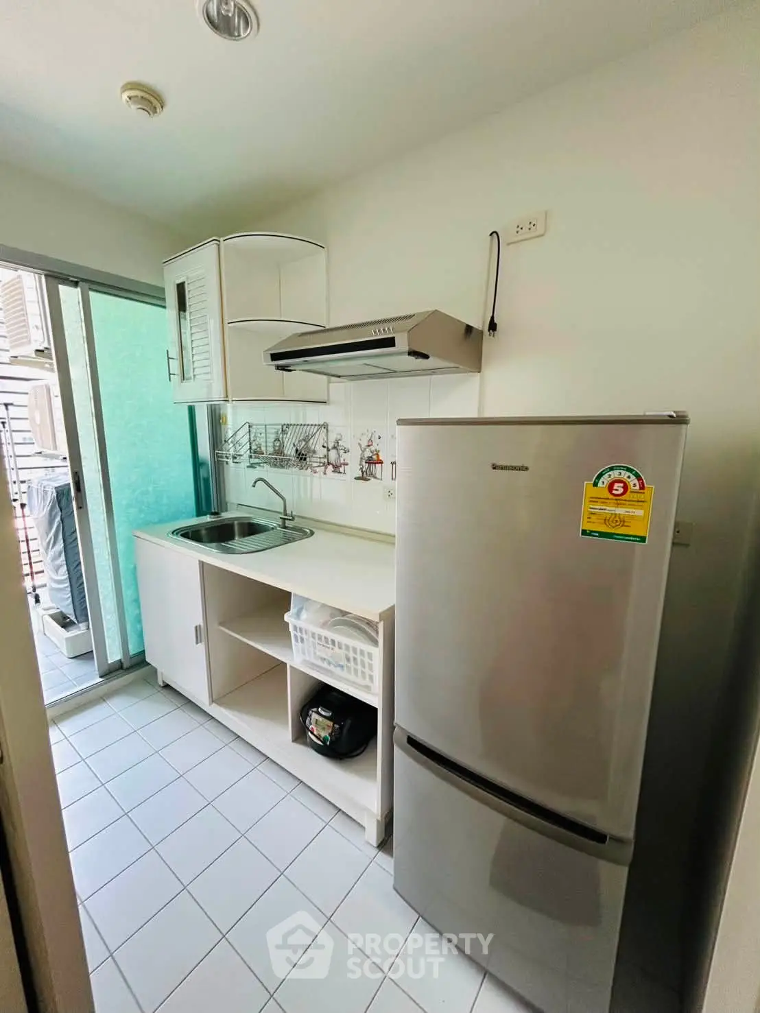 Compact kitchen with modern fridge and sleek cabinetry in a cozy apartment setting.