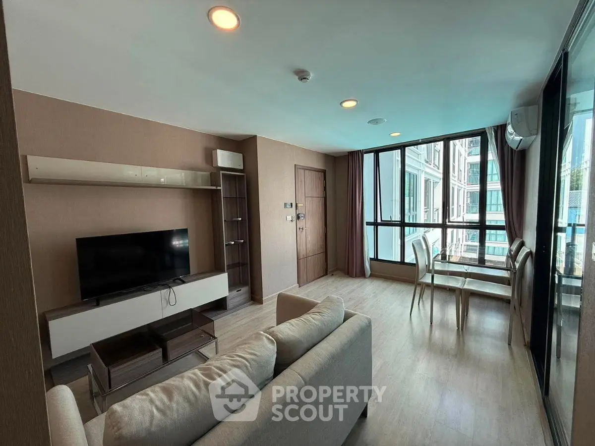 Spacious modern living room with large windows and dining area in a stylish apartment.