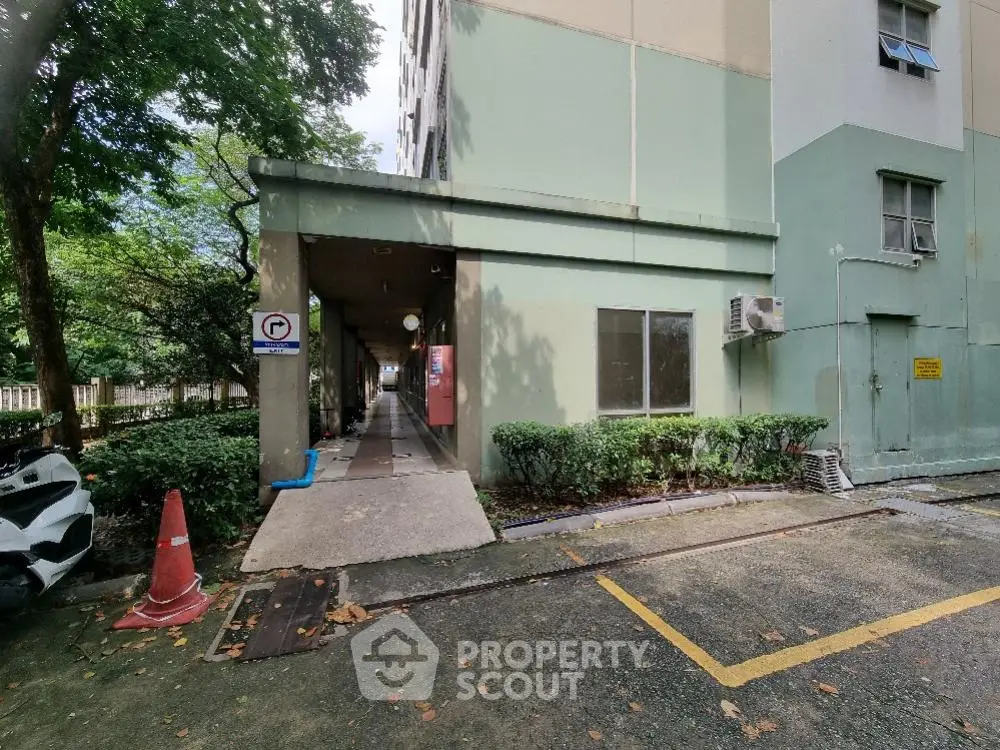 Charming apartment building entrance with lush greenery and convenient parking area.