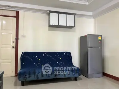 Cozy living room with stylish sofa and modern fridge, perfect for urban living.