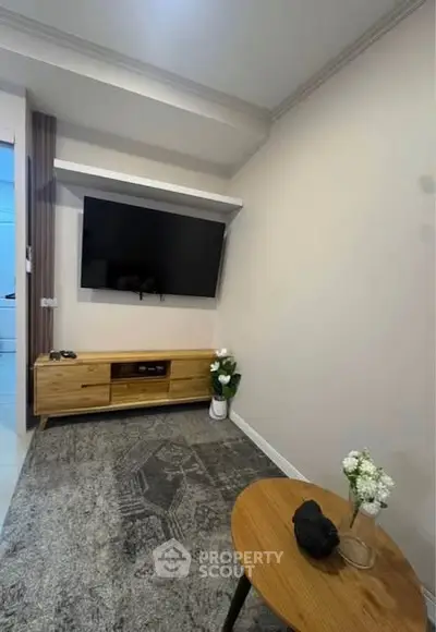 Modern living room with wall-mounted TV and stylish wooden furniture.