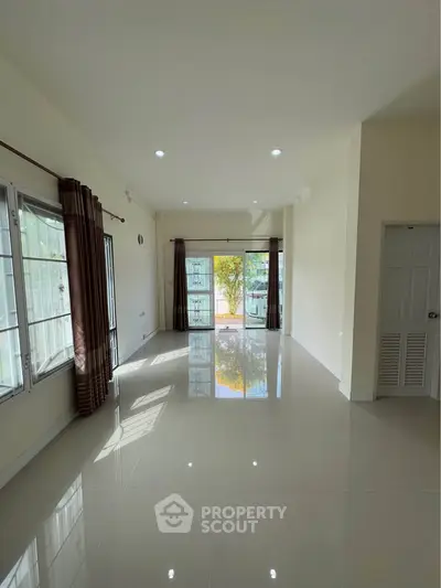Spacious empty living room with large windows and glossy tiled floor