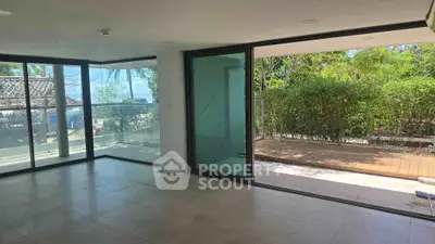Spacious living room with large windows and garden view, perfect for natural light lovers.