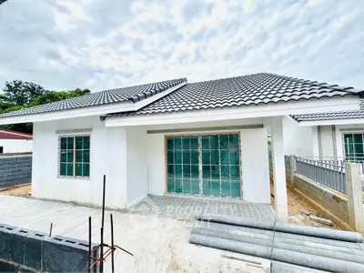 Modern single-story house under construction with tiled roof and large windows.