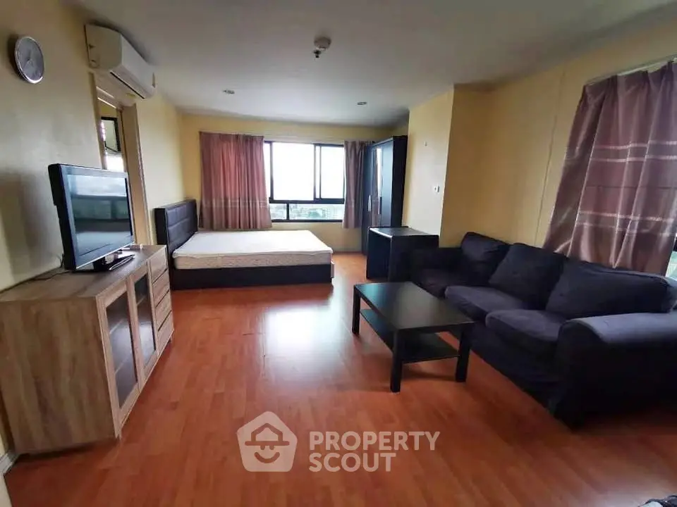 Spacious studio apartment with modern furnishings and large windows offering natural light.