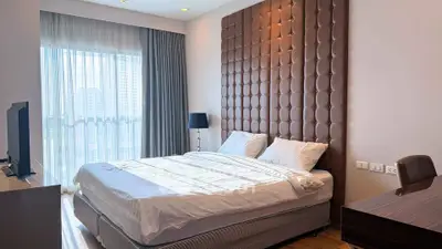 Luxurious bedroom with modern decor and large window offering city views.