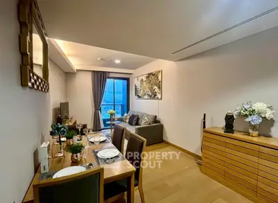 Elegant living room with dining area and modern decor, featuring a cozy sofa and large window view.