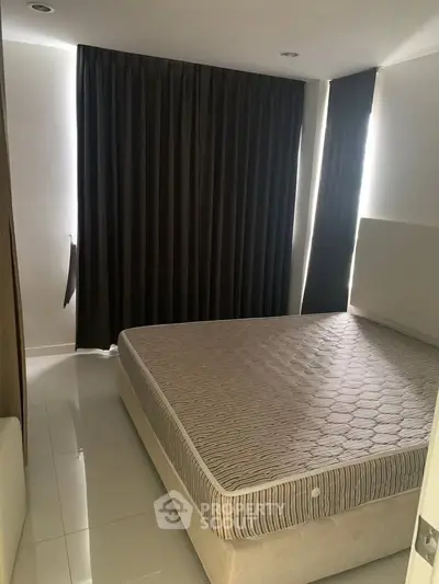 Spacious bedroom with large bed and elegant dark curtains, perfect for restful nights.