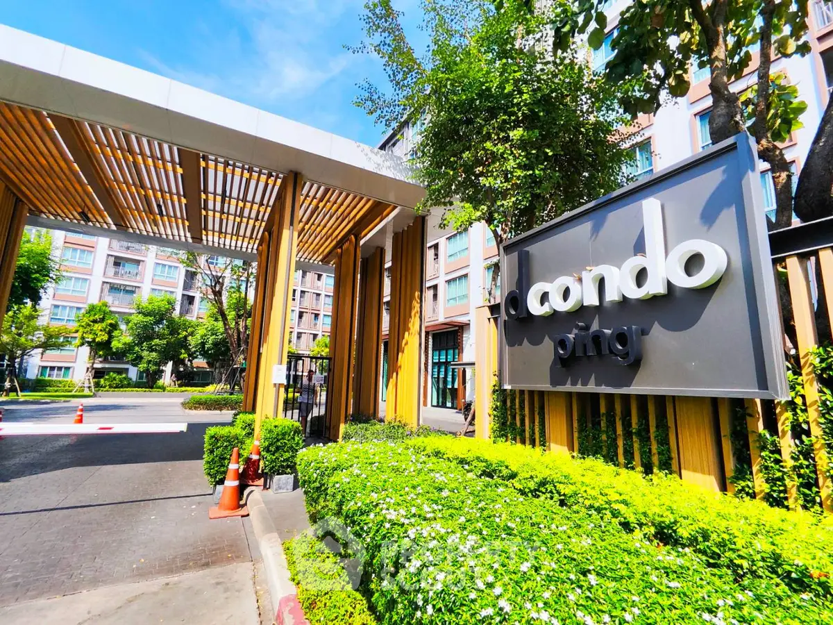 Modern condo entrance with lush greenery and stylish signage, showcasing urban living at its finest.