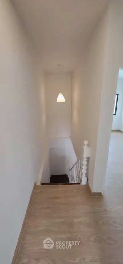 Bright hallway with wooden flooring and staircase leading down, ideal for modern homes.