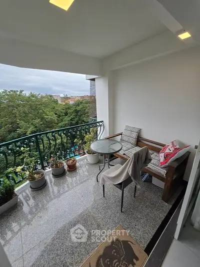 Charming balcony with cozy seating and lush green view, perfect for relaxation.
