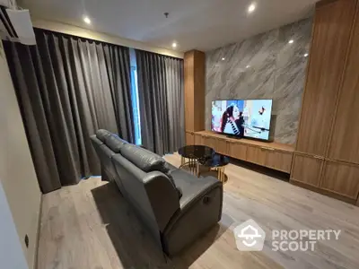 Luxurious living room with modern decor and large TV, perfect for relaxation.