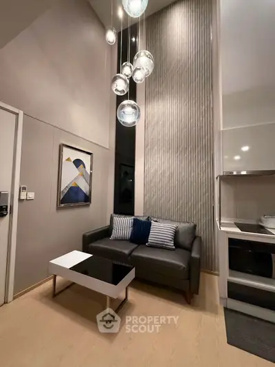 Modern living room with stylish lighting and compact kitchen area in a contemporary apartment.