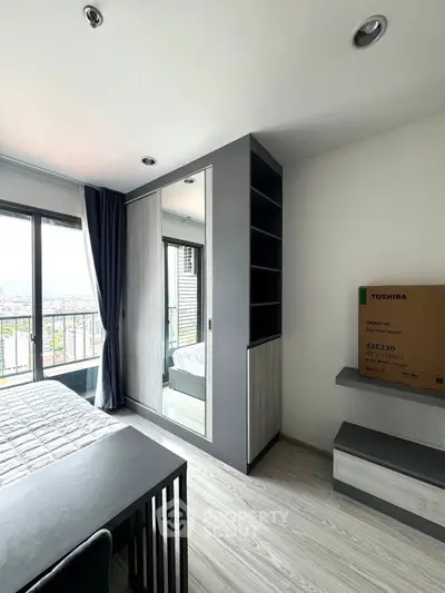 Modern bedroom with sleek furniture and city view from balcony