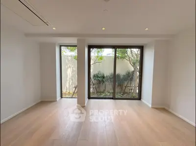 Spacious living room with large windows and garden view, perfect for natural light lovers.