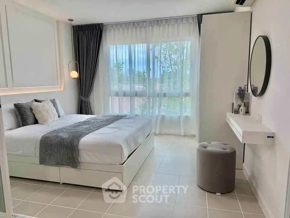 Elegant bedroom with large window and modern decor, perfect for relaxation.