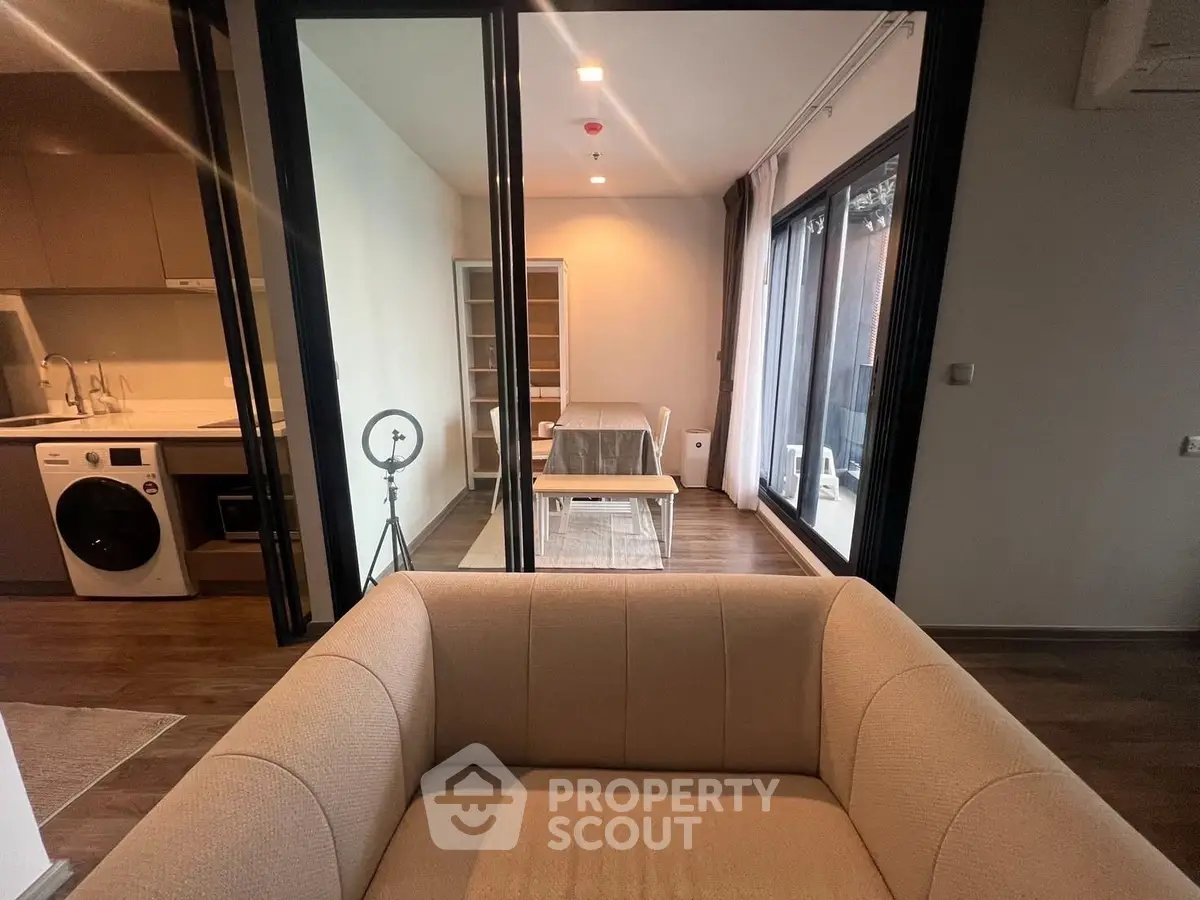 Modern apartment interior with cozy living room and stylish kitchen featuring a washing machine and open layout.