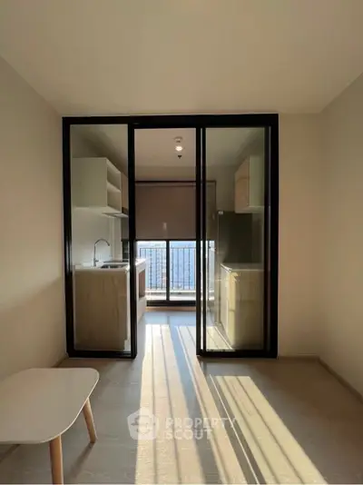 Modern apartment with open kitchen and balcony view, featuring sleek glass doors and ample natural light.