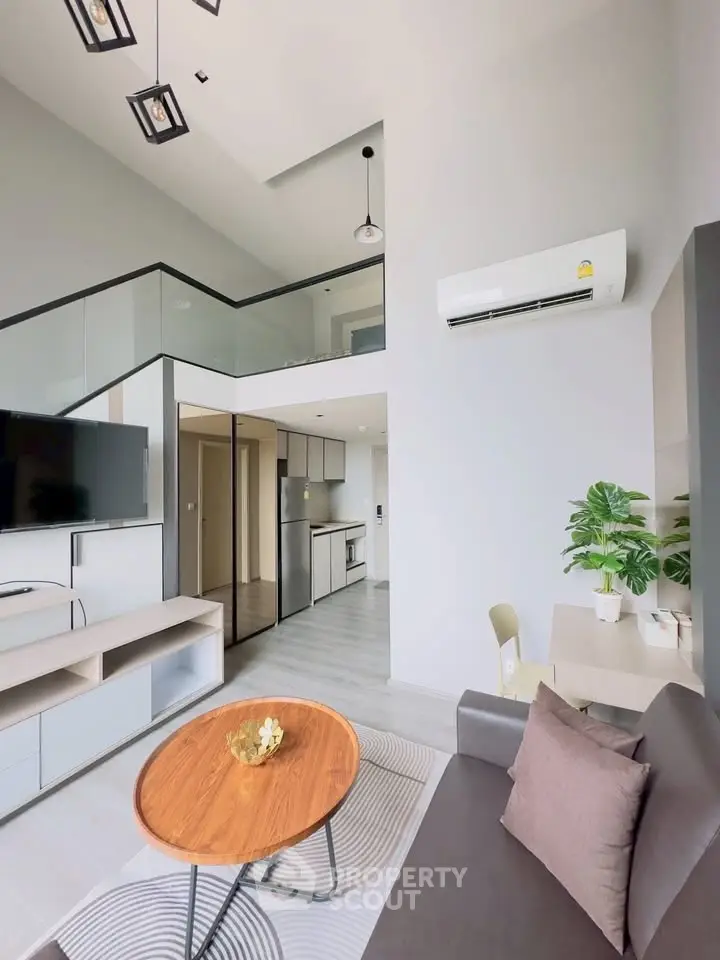 Modern living room with loft design, sleek furniture, and open kitchen layout in a stylish apartment.