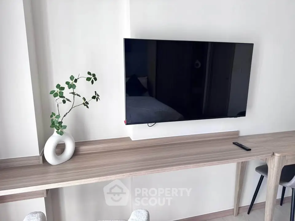 Modern living room with sleek TV and stylish decor on wooden console table.