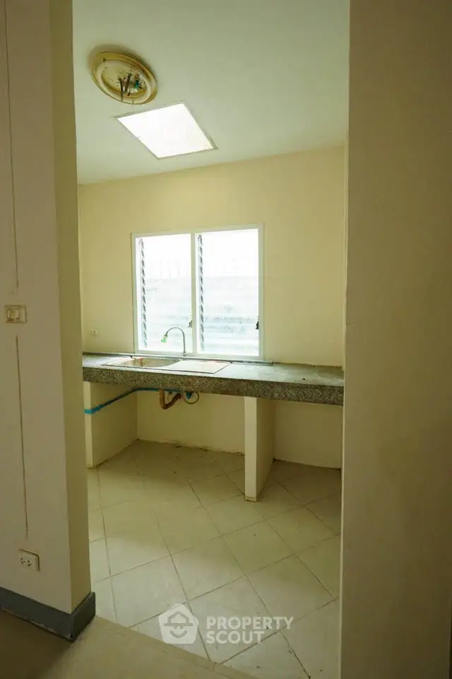 Spacious kitchen area with large window and ample countertop space.