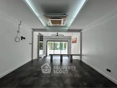 Spacious modern living room with sleek flooring and large windows offering natural light.