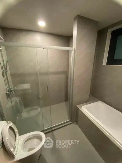 Modern bathroom with sleek shower and bathtub in contemporary apartment.