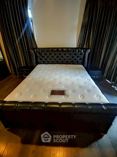 Luxurious bedroom with elegant leather bed and dark curtains, perfect for a sophisticated living space.