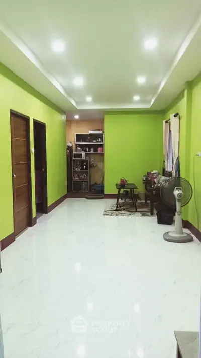 Spacious living room with vibrant green walls and modern lighting