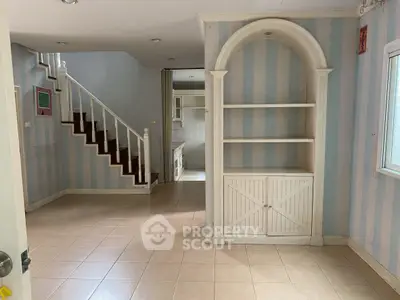 Charming interior with classic staircase and built-in shelving, perfect for cozy living.