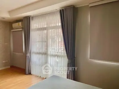 Spacious bedroom with large windows and elegant curtains, featuring natural light and modern design.