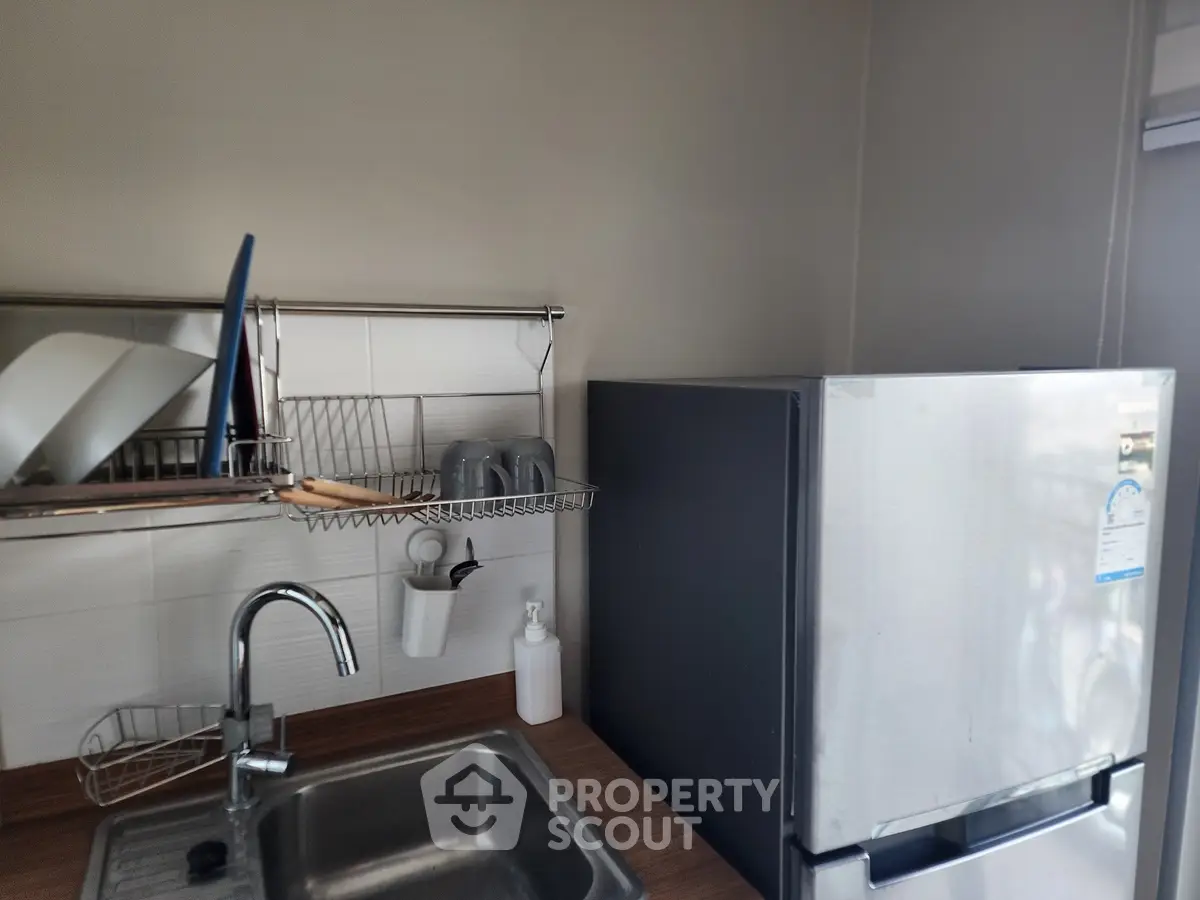 Modern kitchen with sleek fridge and dish rack, featuring a compact yet functional design.