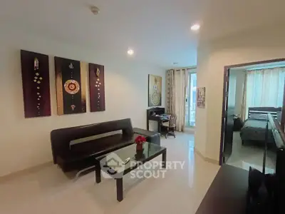 Modern living room with elegant decor and adjacent bedroom, featuring stylish furniture and ambient lighting.