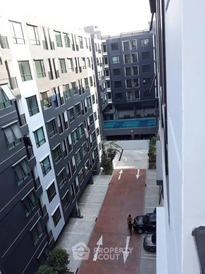 Modern apartment complex with pool and parking area, showcasing urban living.