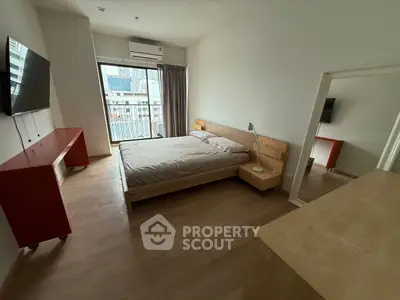 Spacious bedroom with modern furnishings and city view balcony access.