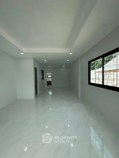 Spacious modern living room with large windows and sleek white flooring, perfect for natural light and open living.
